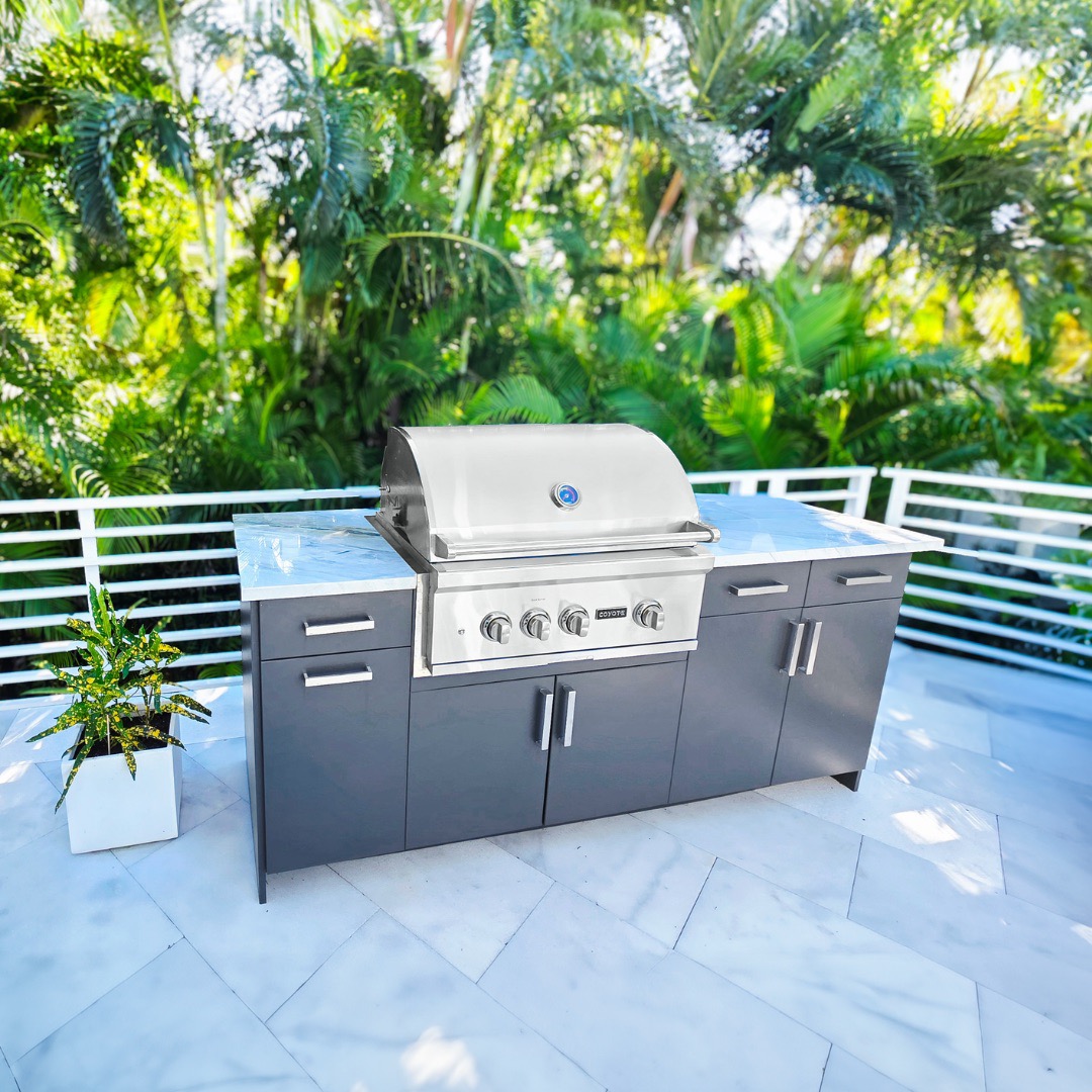 Modern outdoor kitchen with a built-in stainless steel grill and gray cabinetry on a Florida patio.